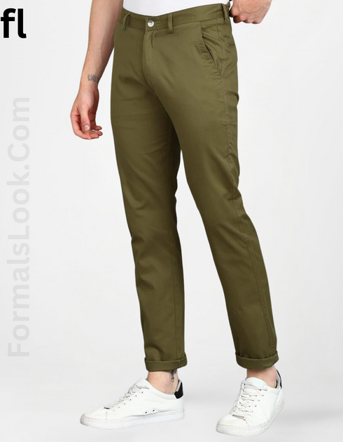 A person standing wearing light green slim-fit chino pants and white sneakers.