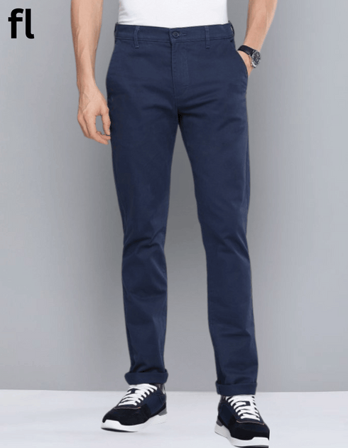 A man standing against a grey background, wearing navy cotton imported stuff pants with a smart fit.